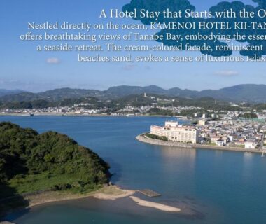 Curved bay and coastal town with hotel complex at Kii-Tanabe, Wakayama, framed by green peninsula and distant hills