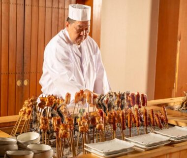 Ryokan chef arranging skewers on wooden counter at KAMENOI HOTEL Nikko Yunishigawa in Tochigi