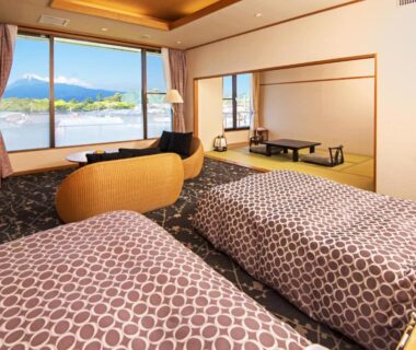 Twin beds and tatami seating with low table, large window framing water and distant mountains