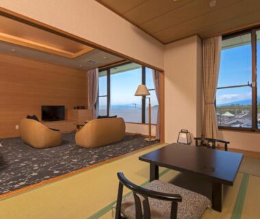 Tatami room with low table and lounge chairs at KKR Numazu Hamayu, Shizuoka
