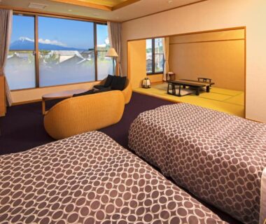 Twin beds with tatami seating area, low table and window view at KKR Numazu Hamayu Shizuoka