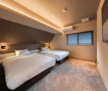 Twin beds in contemporary room at KOS Restaurant & Hotel, Yamanashi with soft lighting and window blinds