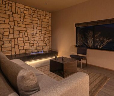 Cozy lounge with sofa, stone accent wall and low table at KOS Restaurant & Hotel in Yamanashi, Chūbu, Japan