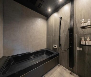 Black soaking tub with wall-mounted shower in a modern bathroom at KOS Restaurant & Hotel, Yamanashi