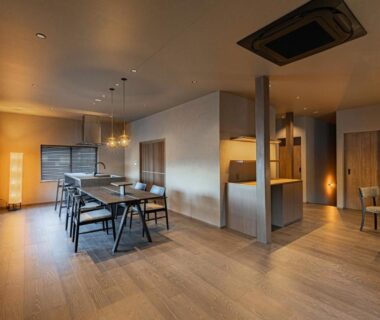 Spacious minimalist dining area with long wooden table, chairs, pendant lights at KOS Restaurant & Hotel in Yamanashi
