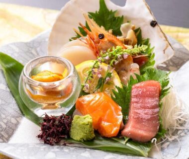 Assorted sashimi, prawns, and garnishes on ceramic plate at Kagariya ryokan, Hokkaidō