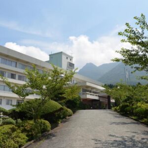Paved entrance and landscaped shrubs leading to Kagetsuen ryokan with mountain backdrop in Kanagawa, Kantō