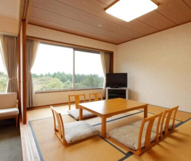 Traditional tatami room with low table, zaisu chairs and large window with green view at Kagetsuen Kanagawa