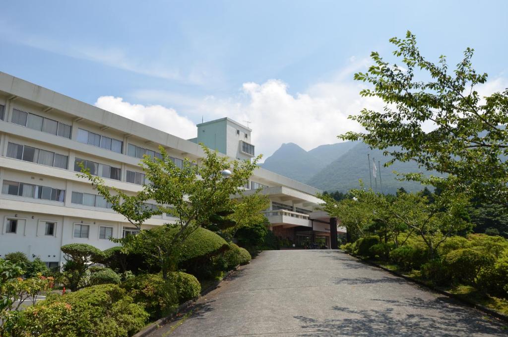 Exterior driveway at Kagetsuen Kanagawa Paved entrance and landscaped shrubs leading to Kagetsuen ryokan with mountain backdrop in Kanagawa, Kantō