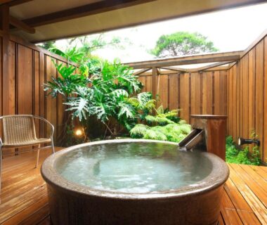 Round wooden bath on deck with wooden fence, plants and chair at Kagetsutei in Shizuoka