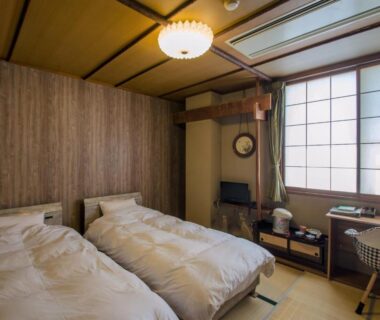 Tatami-floored room with two beds, shoji screens, wooden wall and desk at Kaigetsu, Mie