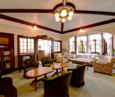 Ryokan lounge with sofas, armchairs, wooden tables, bookshelf and chandelier at Kaihinsou Kamakura in Kanagawa