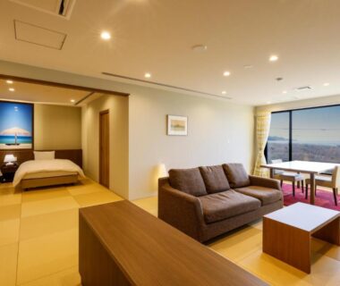 Modern tatami room with sofa, twin beds and large city window at Kaikatei Hanagozen, Kyoto
