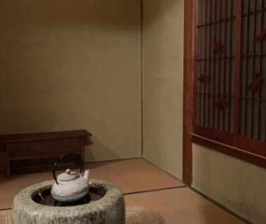 Traditional tatami room with stone hearth, kettle, woven floor cushions and wooden lattice window at Kairi, Hyōgo