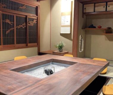 Traditional sunken irori table with low chairs and tatami flooring in Kairi ryokan dining room, Hyōgo