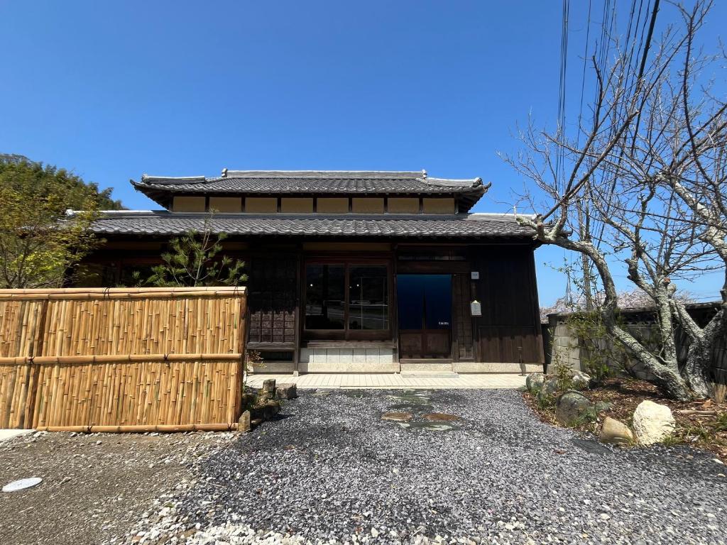 Wooden ryokan entrance at Kairi Hyōgo Traditional wooden facade with tiled roof, bamboo fence and gravel courtyard at Kairi in Hyōgo
