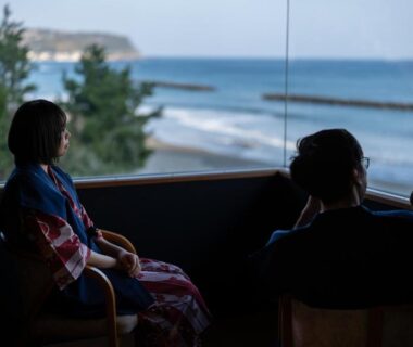 Two guests in yukata gazing at seaside through a large window at Kaiyutei, Shizuoka