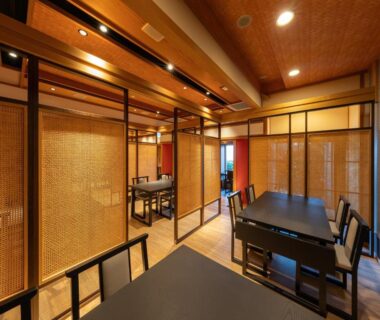 Partitioned dining area with wooden lattice screens, tables and chairs and warm ambient lighting at Kaiyutei, Shizuoka