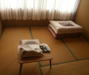 Tatami room with stacked futon and low table at Kakiya Ryokan in Kanagawa