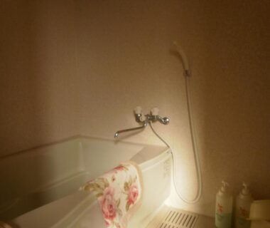 Small bathtub with handheld shower, floral towel and toiletries at Kakiya Ryokan Kanagawa
