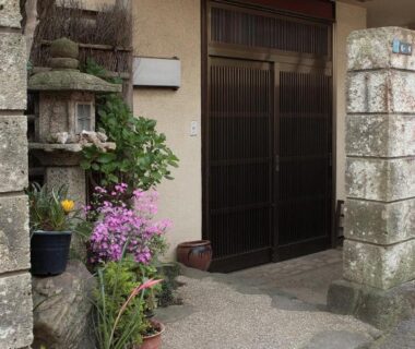 Entrance with stone lantern, potted plants, and sliding wooden door at Kakiya Ryokan in Kanagawa