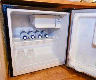 Open minibar fridge with bottled water and glasses in a ryokan room at Kamegawa Onsen HATAGO Yuyu, Ōita