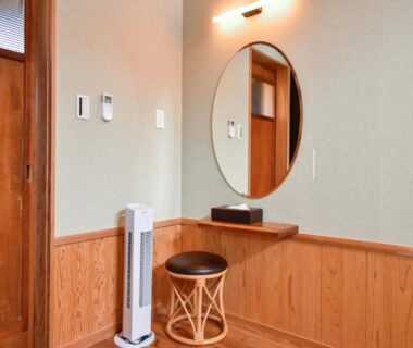 Wood-paneled dressing nook with round mirror at Kamegawa Onsen HATAGO Yuyu in Ōita, Kyūshū