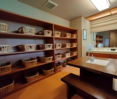 Changing area with wicker baskets, wooden bench, sinks and mirrors at Kameya Ean in Shizuoka
