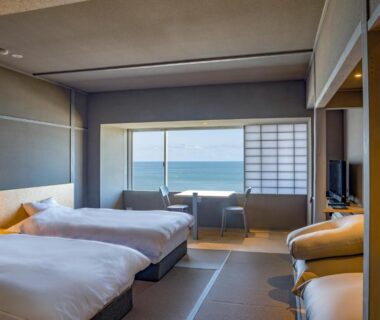 Twin beds with tatami flooring and shoji screen overlooking the sea at Kameya Hotel in Yamagata, Tōhoku, Japan