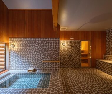Indoor tiled onsen bath with wooden wall panels and bench seating at Kameya Hotel, Yamagata