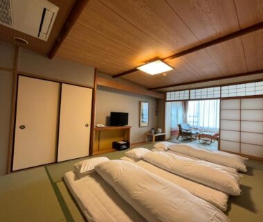 Three futons on tatami, shoji screens and seating area at Kameya Rakan in Chubu, Shizuoka