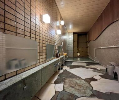 Indoor bathing area with stone floor, washing stools and mirrors at Kameya Rakan in Shizuoka