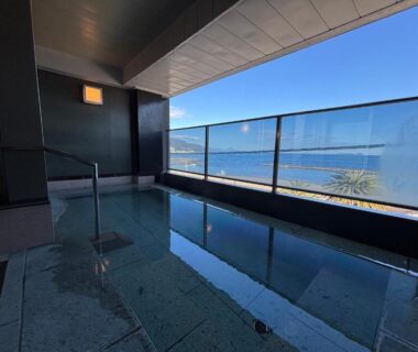 Tiled indoor onsen bath with glass railing and coastal view at Kameya Rakan, Shizuoka, Chūbu, Japan