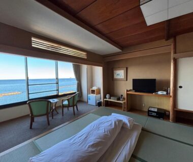 Tatami room with futon, low table, chairs and ocean view at Kameya Rakan in Shizuoka Chūbu