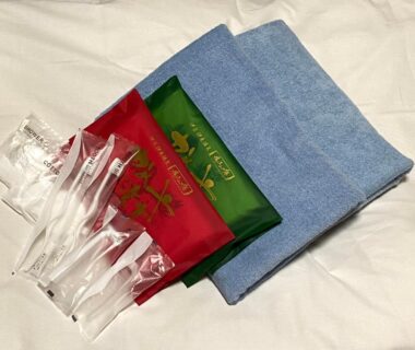 Folded blue towels with individually wrapped toothbrushes and packaged toiletries at Kameya Rakan, Shizuoka