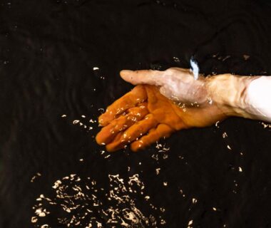 Hand dipping into dark water at Kameyama Onsen Hotel, Chiba, Kantō