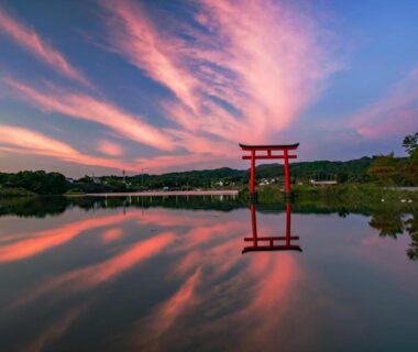 Red torii gate reflected on calm water at dusk near Kameyama Onsen Hotel, Chiba, Kantō