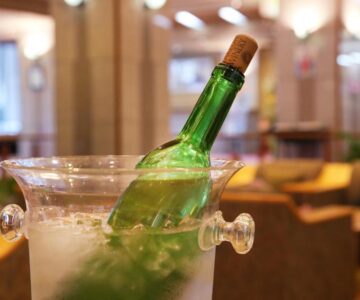 Green bottle in ice bucket on table, lounge seating blurred at Kami no yama Azumaya Yamagata