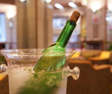 Green bottle in ice bucket on table, lounge seating blurred at Kami no yama Azumaya Yamagata