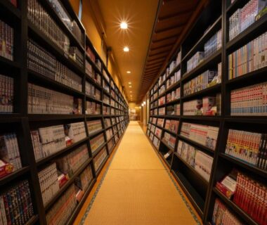 Long corridor lined with manga shelves and soft lighting at Kami no yama Azumaya, Yamagata