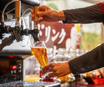 Hand pouring draft beer from tap at Kami no yama Azumaya in Yamagata