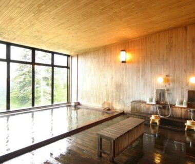Indoor wooden onsen with large windows and shower stations at Kamihoroso Hokkaidō