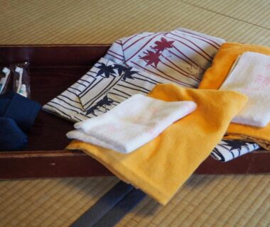 Folded yukata and towels on wooden tray on tatami mat in ryokan room