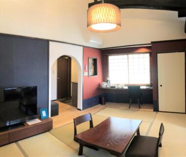 Tatami room with low table, shoji window and television at Kamishichiken Oku in Kyoto