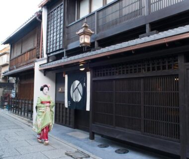 Traditional wooden frontage of Kamishichiken Oku with noren and woman in kimono on Kyoto street