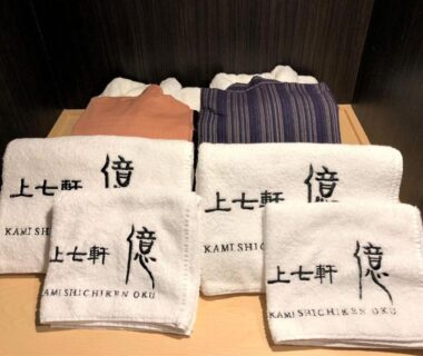 Folded embroidered towels and yukata on shelf at Kamishichiken Oku ryokan, Kyoto