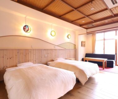 Bright twin room with wooden ceiling and seating at Kamiyamada Hotel Nagano