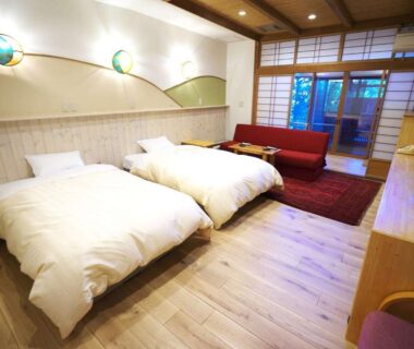 Twin beds in bright ryokan room with shoji screens and seating area at Kamiyamada Hotel, Nagano