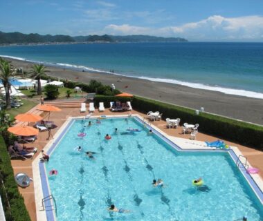 Outdoor swimming pool and sun loungers beside sandy beach at Kamogawa Grand Hotel Chiba