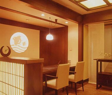 Warm wooden dining alcove with table, chairs, shoji-style partition and pendant light at Kamogawakan in Kyoto